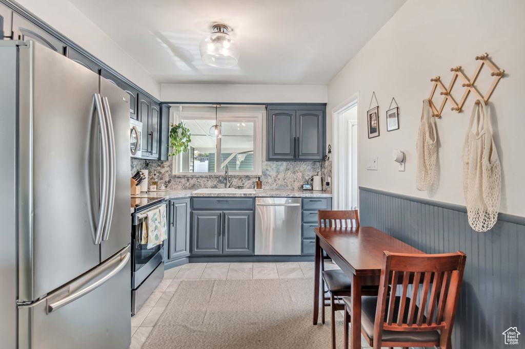 Kitchen with backsplash, sink, stainless steel appliances, and light tile flooring