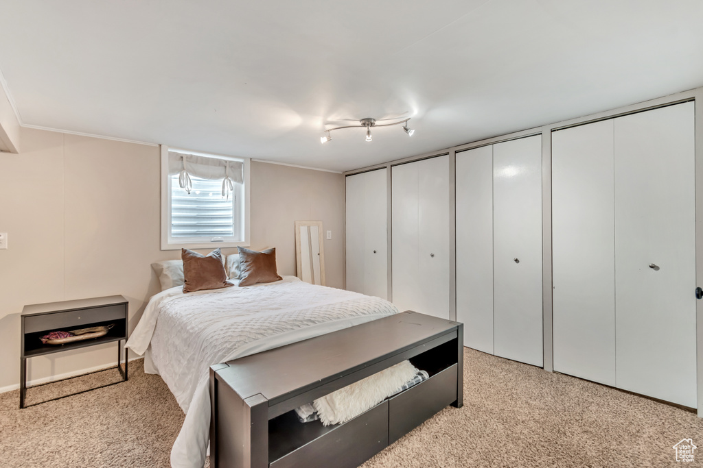 Carpeted bedroom with track lighting and multiple closets
