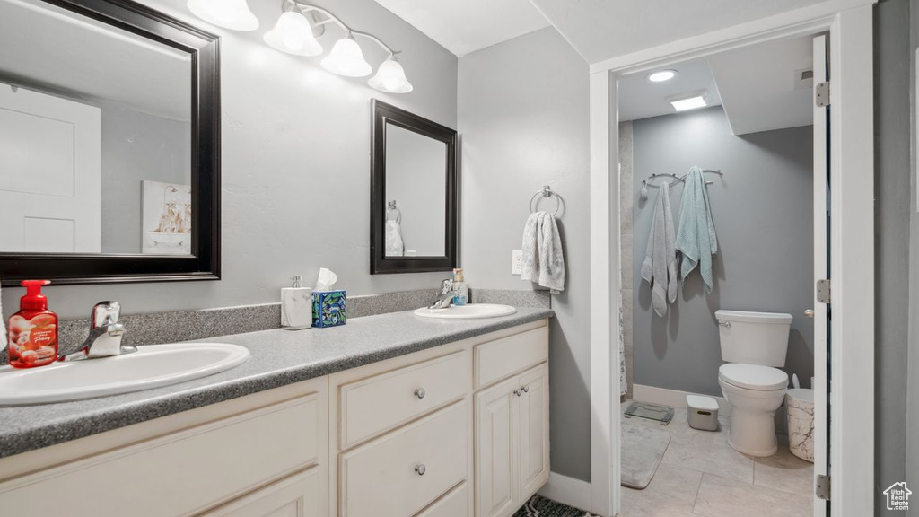 Bathroom featuring tile floors, toilet, and dual bowl vanity