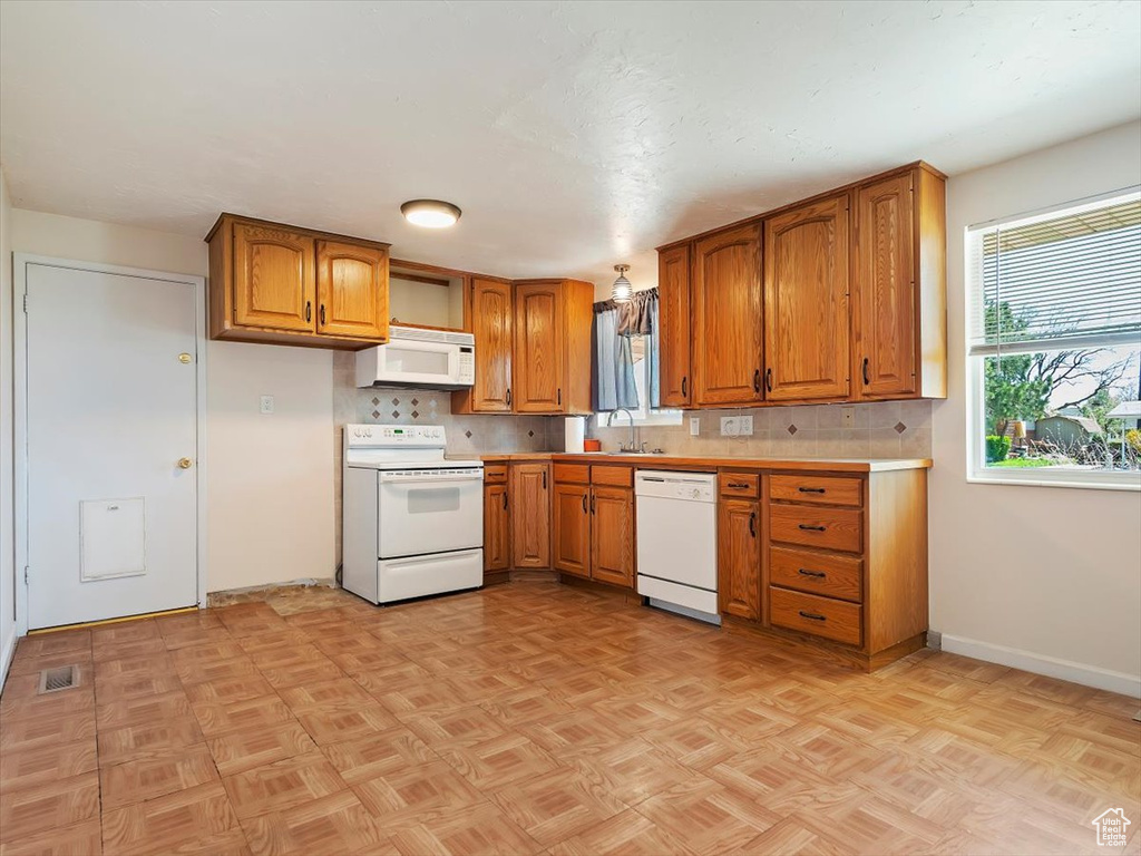 Kitchen featuring backsplash, light parquet floors, white appliances, and sink