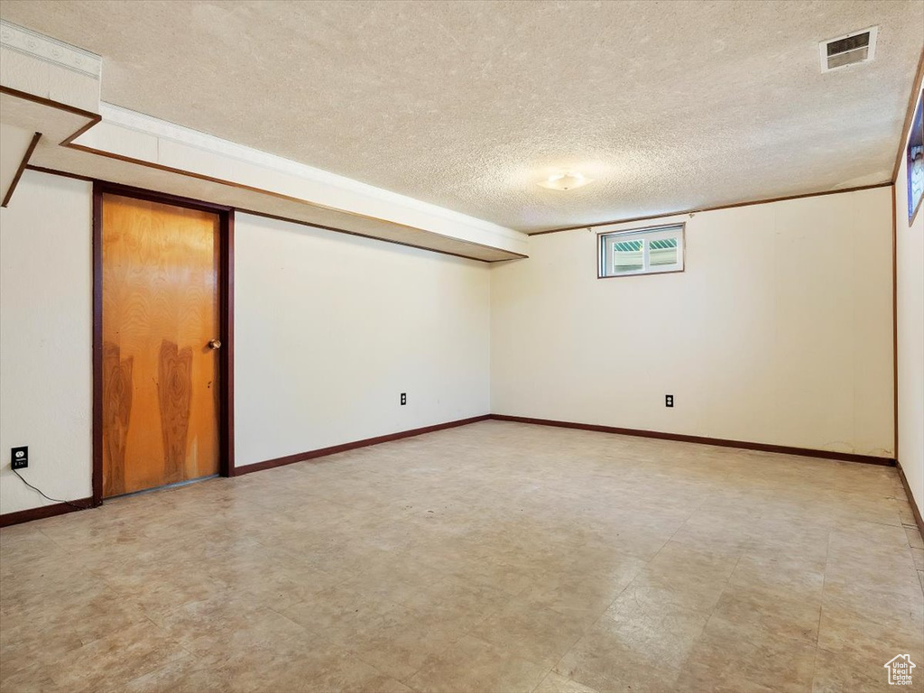 Basement featuring light tile floors and a textured ceiling