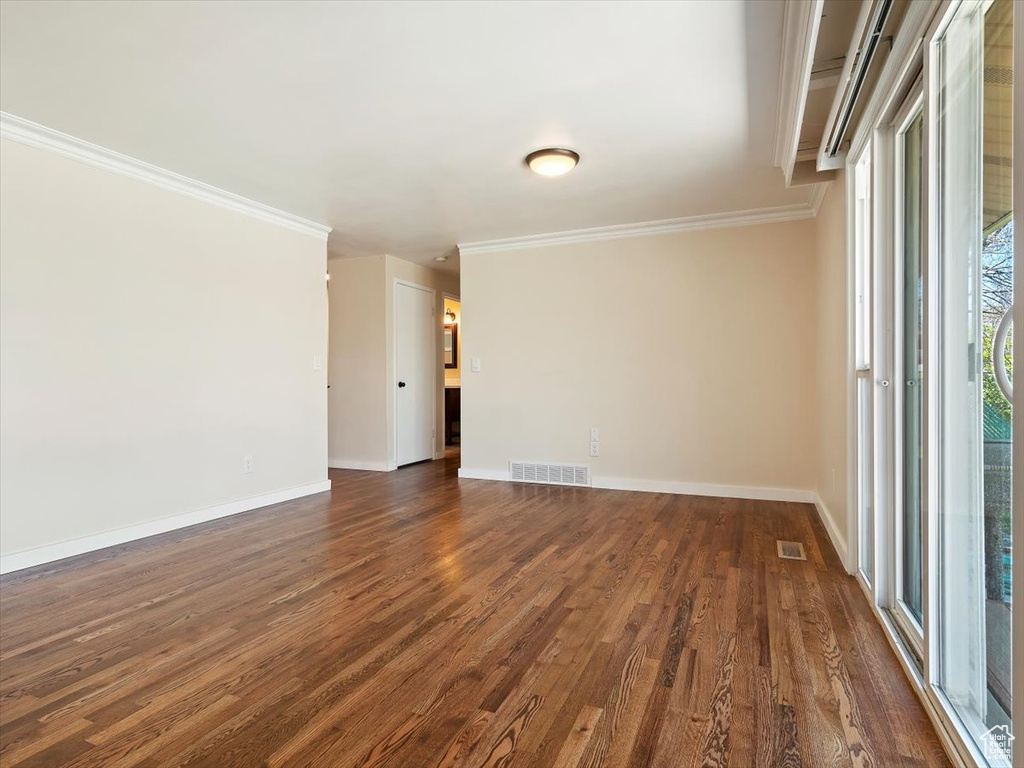 Empty room with ornamental molding and dark hardwood / wood-style flooring