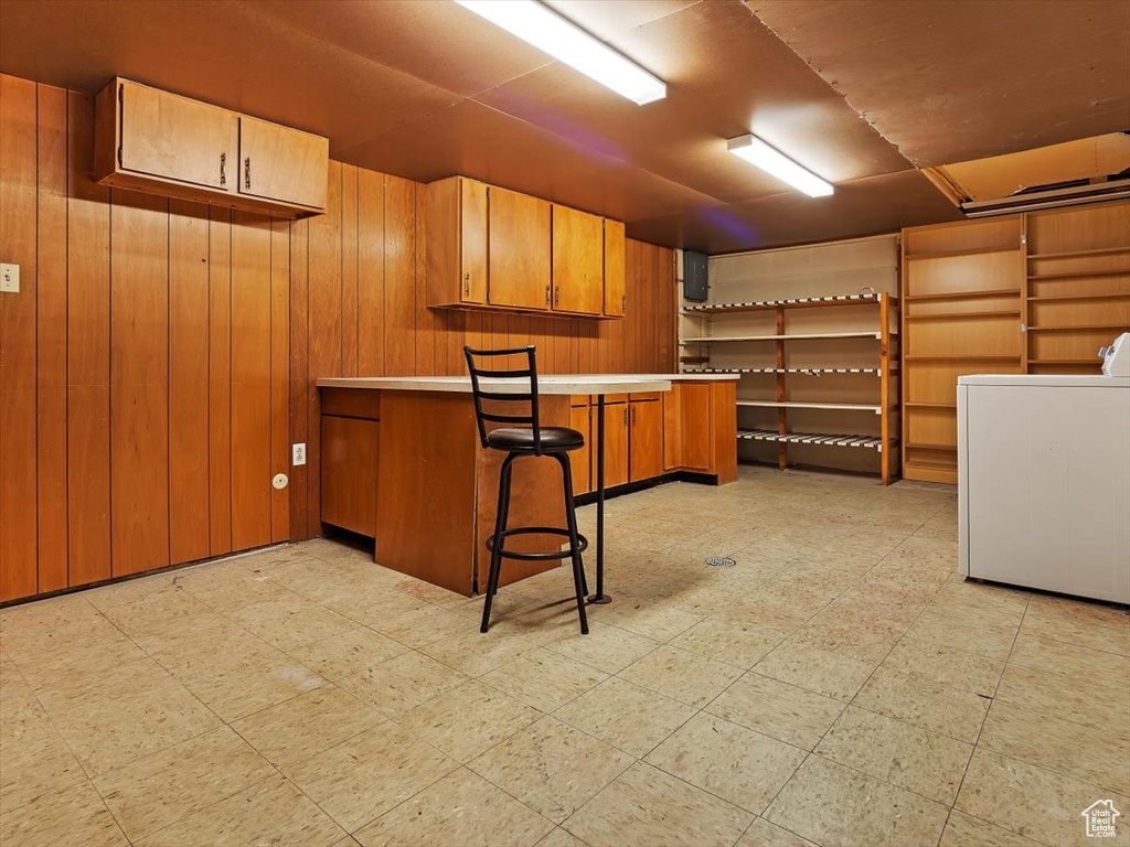 Basement with wood walls, washer / dryer, and light tile floors