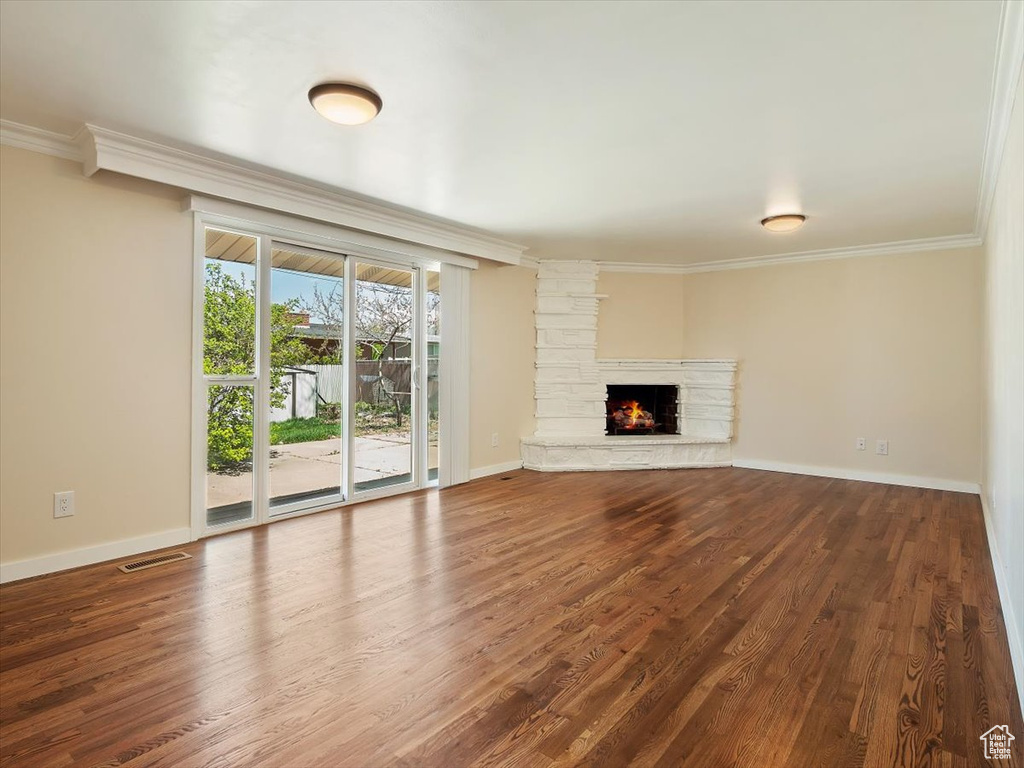 Unfurnished living room with a fireplace, dark hardwood / wood-style flooring, and crown molding