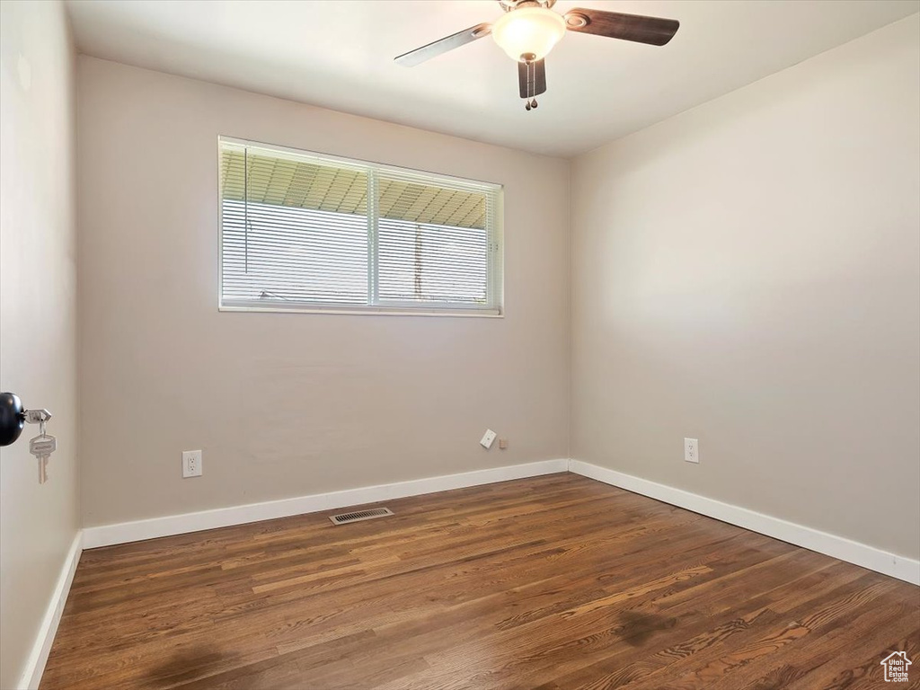 Unfurnished room with dark wood-type flooring and ceiling fan