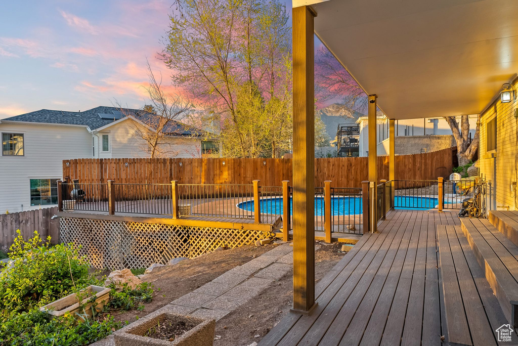 Deck at dusk featuring a fenced in pool