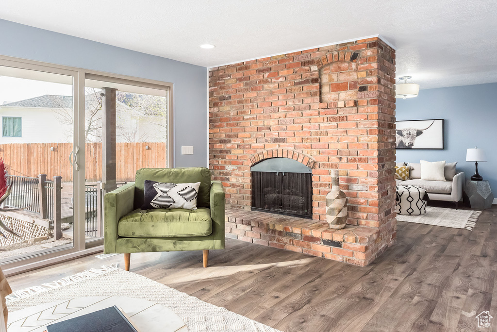 Living area featuring a fireplace, hardwood / wood-style floors, and brick wall