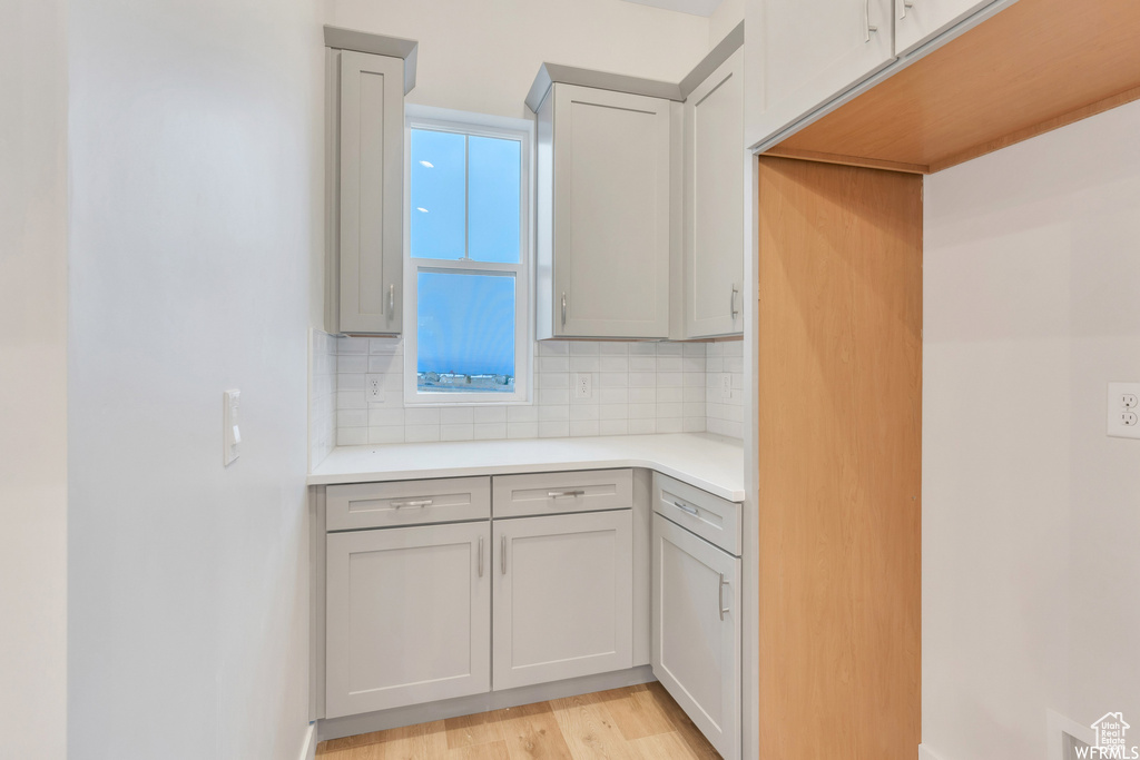Kitchen featuring tasteful backsplash, light wood-type flooring, and gray cabinets