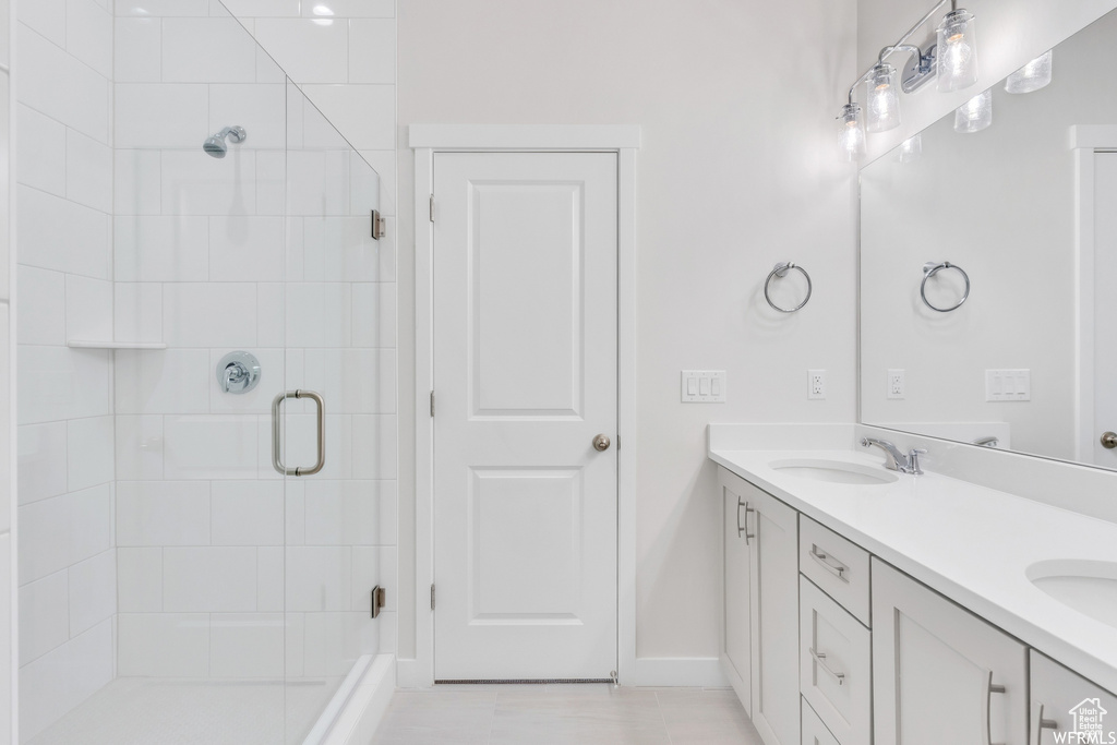 Bathroom with walk in shower, large vanity, tile floors, and dual sinks