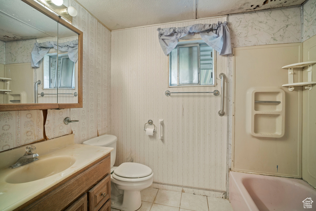 Full bathroom with toilet, a textured ceiling, vanity, bathtub / shower combination, and tile floors