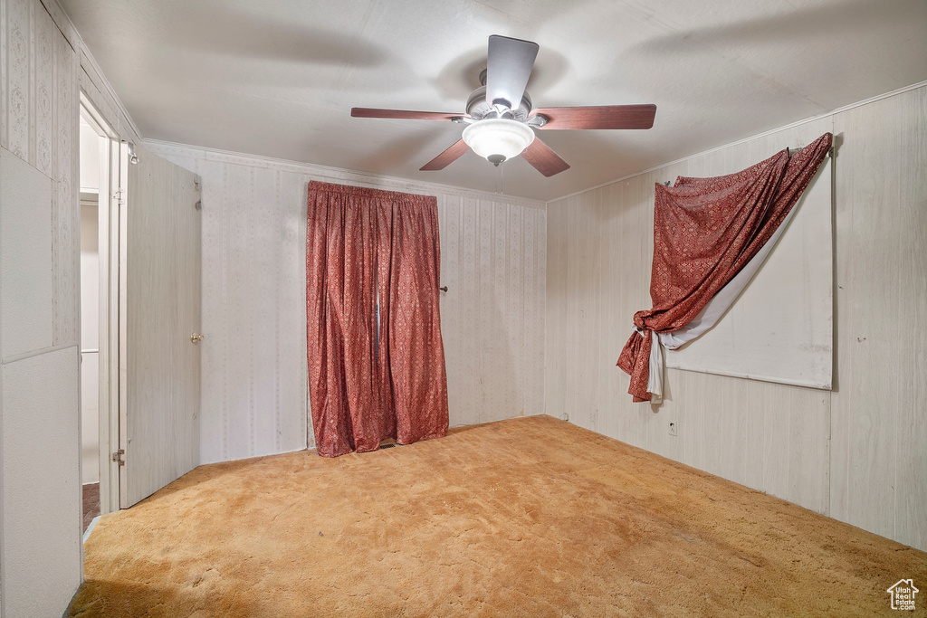 Carpeted spare room featuring ceiling fan and crown molding