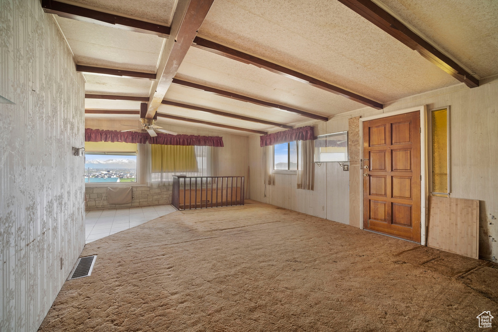Carpeted spare room featuring a textured ceiling, beam ceiling, and ceiling fan