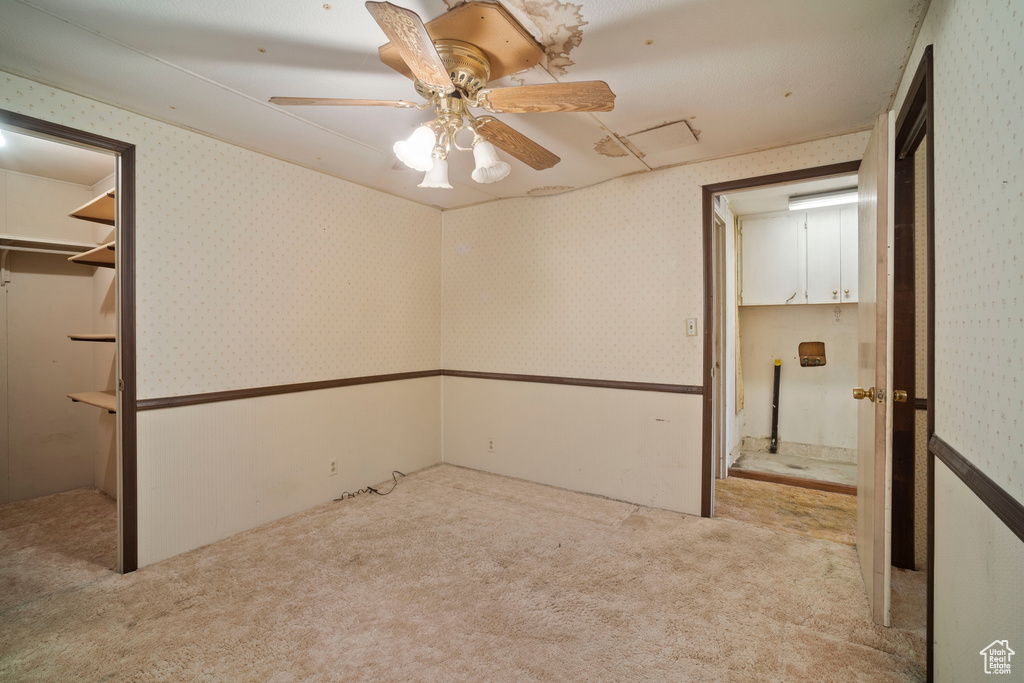 Unfurnished bedroom with a closet, ceiling fan, a walk in closet, and carpet flooring