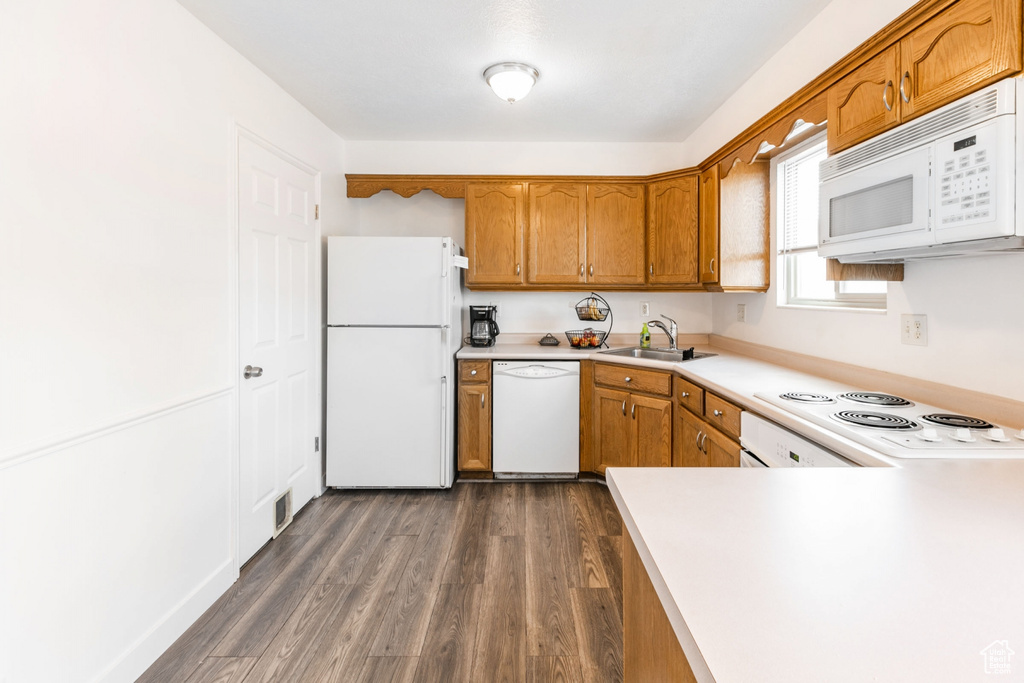 Kitchen with white appliances, dark wood-type flooring, and sink
