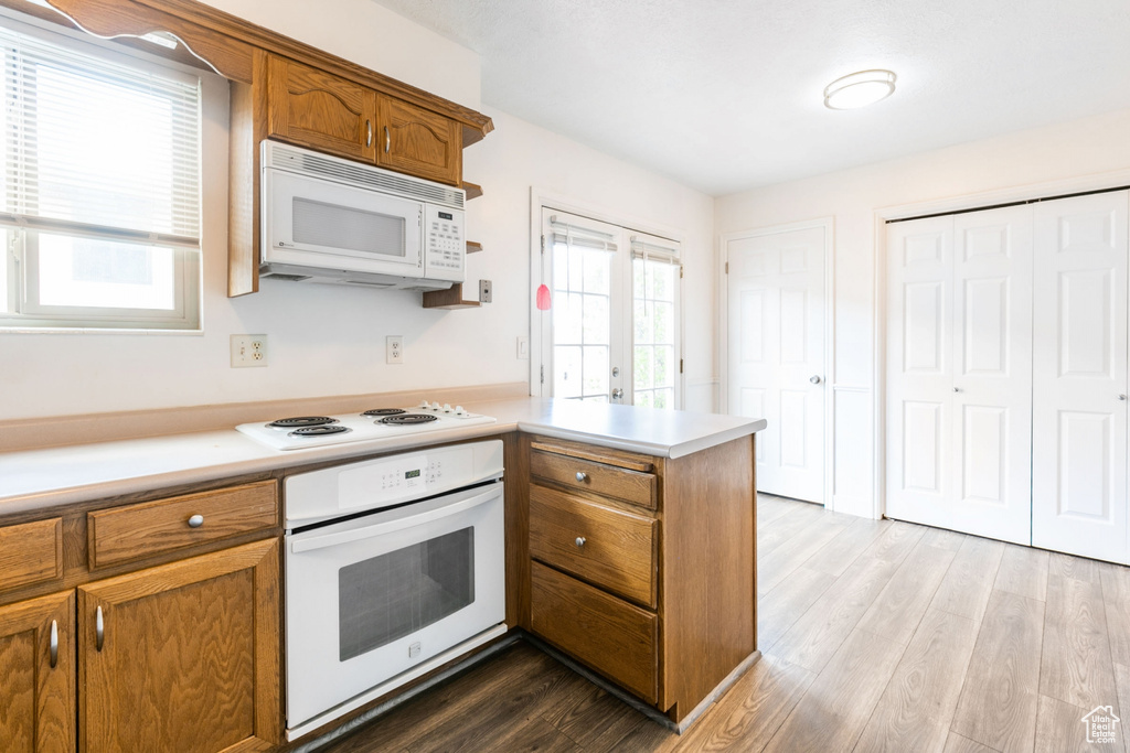 Kitchen featuring white appliances, kitchen peninsula, hardwood / wood-style flooring, and french doors
