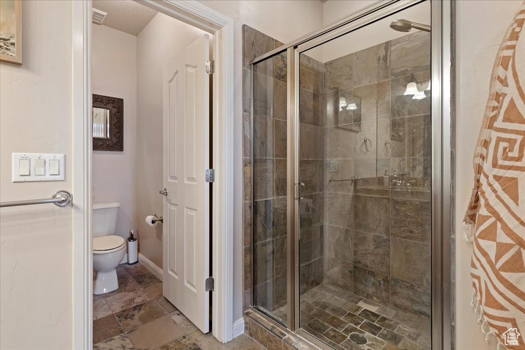Bathroom with walk in shower, tile floors, and toilet
