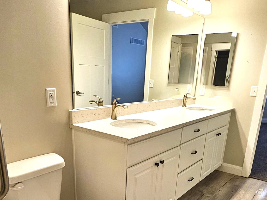 Bathroom with hardwood / wood-style floors, toilet, and dual bowl vanity