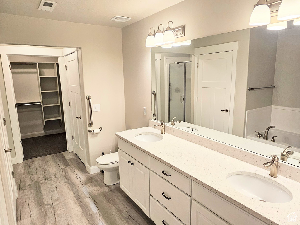 Full bathroom with wood-type flooring, independent shower and bath, toilet, and double sink vanity