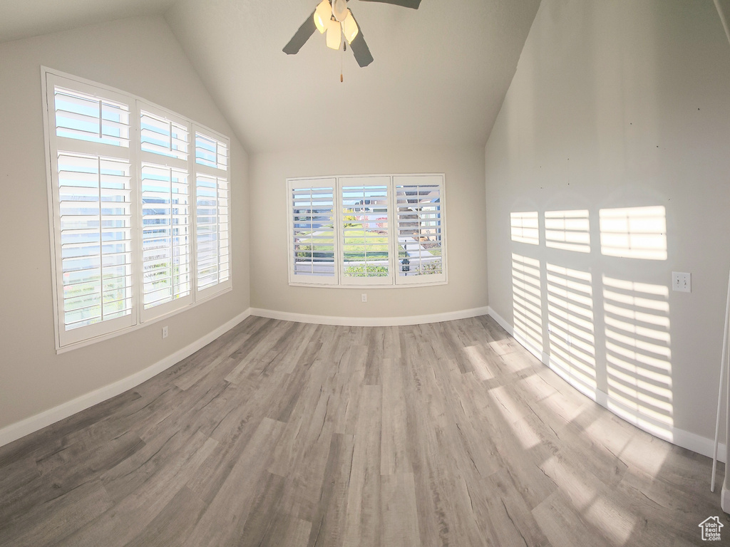Empty room featuring a wealth of natural light, ceiling fan, hardwood / wood-style floors, and vaulted ceiling