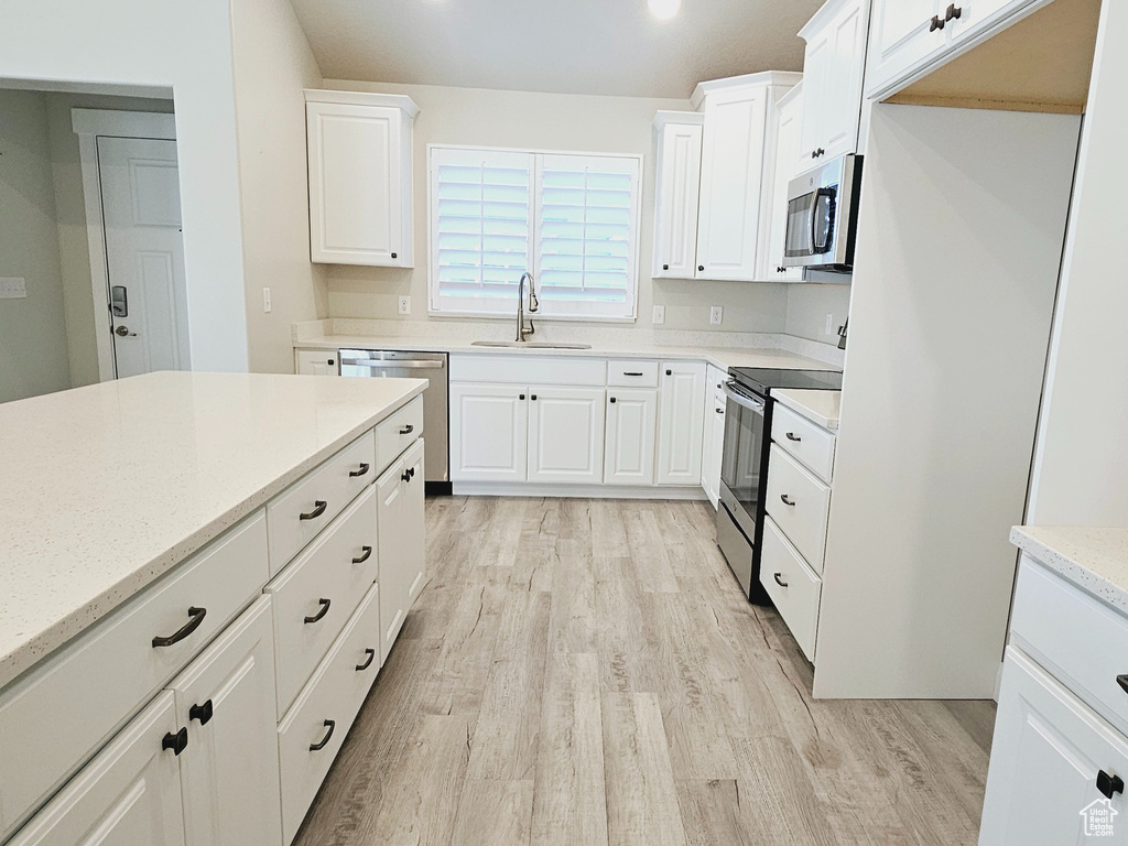 Kitchen featuring white cabinets, light hardwood / wood-style flooring, sink, and stainless steel appliances