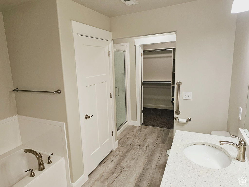 Bathroom featuring wood-type flooring, vanity, and separate shower and tub