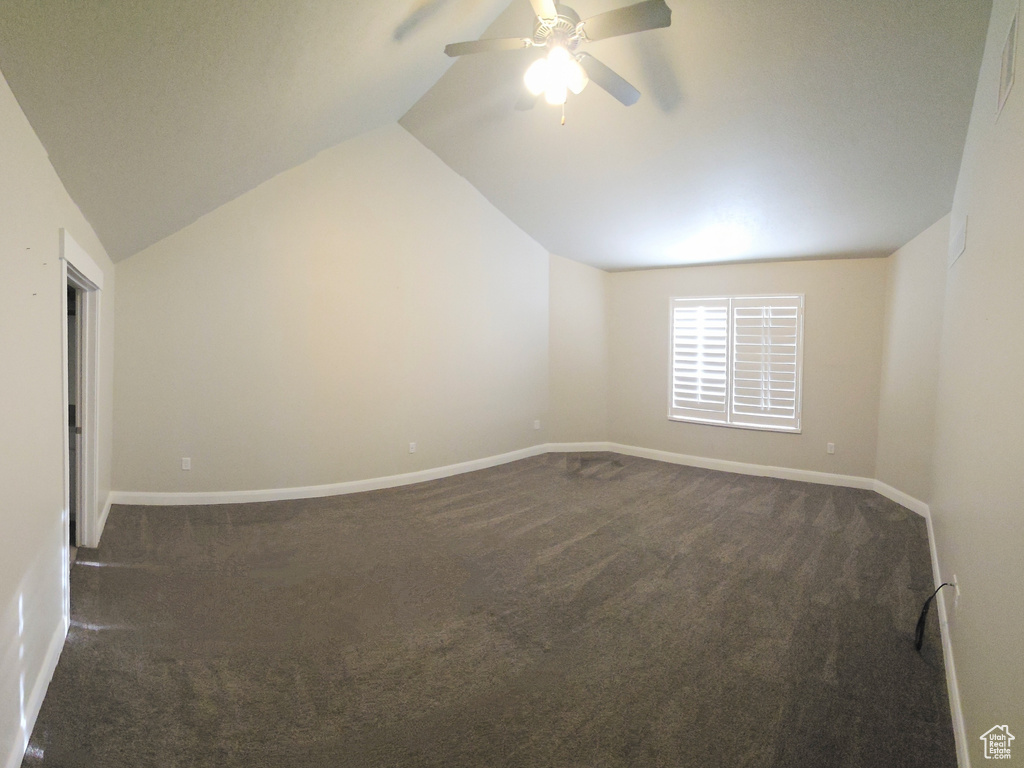 Additional living space featuring dark colored carpet, ceiling fan, and lofted ceiling