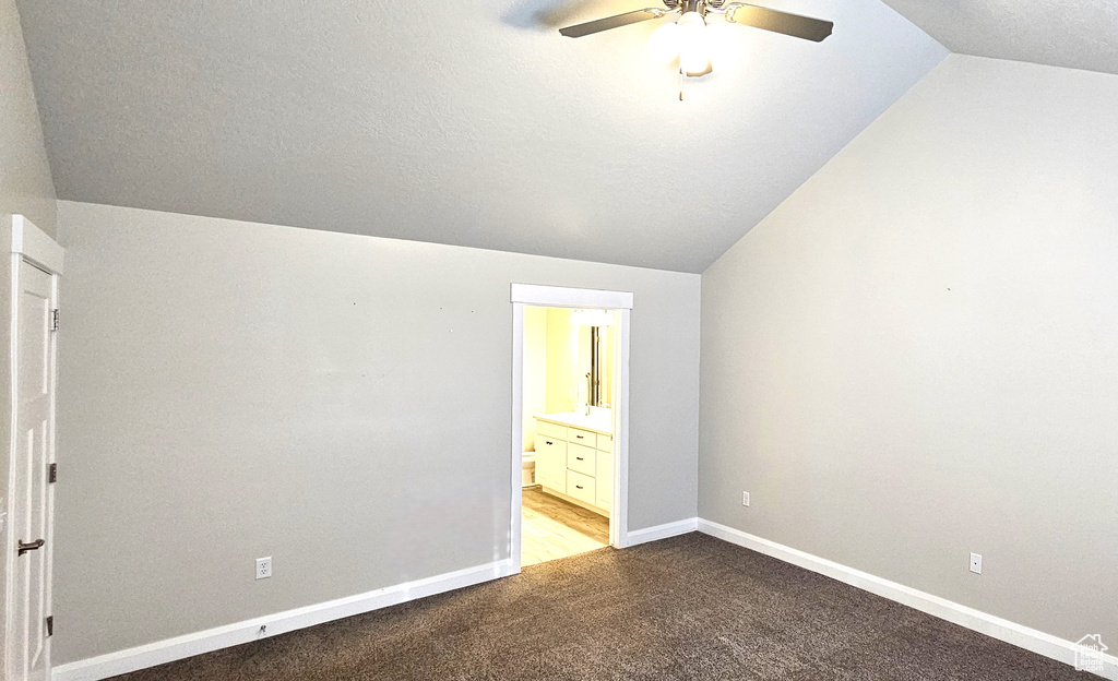 Unfurnished bedroom featuring light colored carpet, connected bathroom, ceiling fan, and lofted ceiling