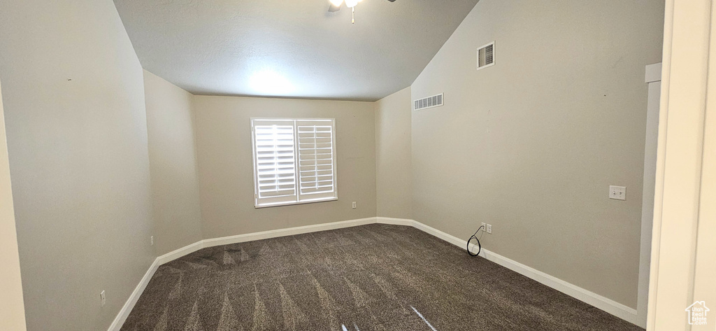 Unfurnished room with lofted ceiling and dark carpet