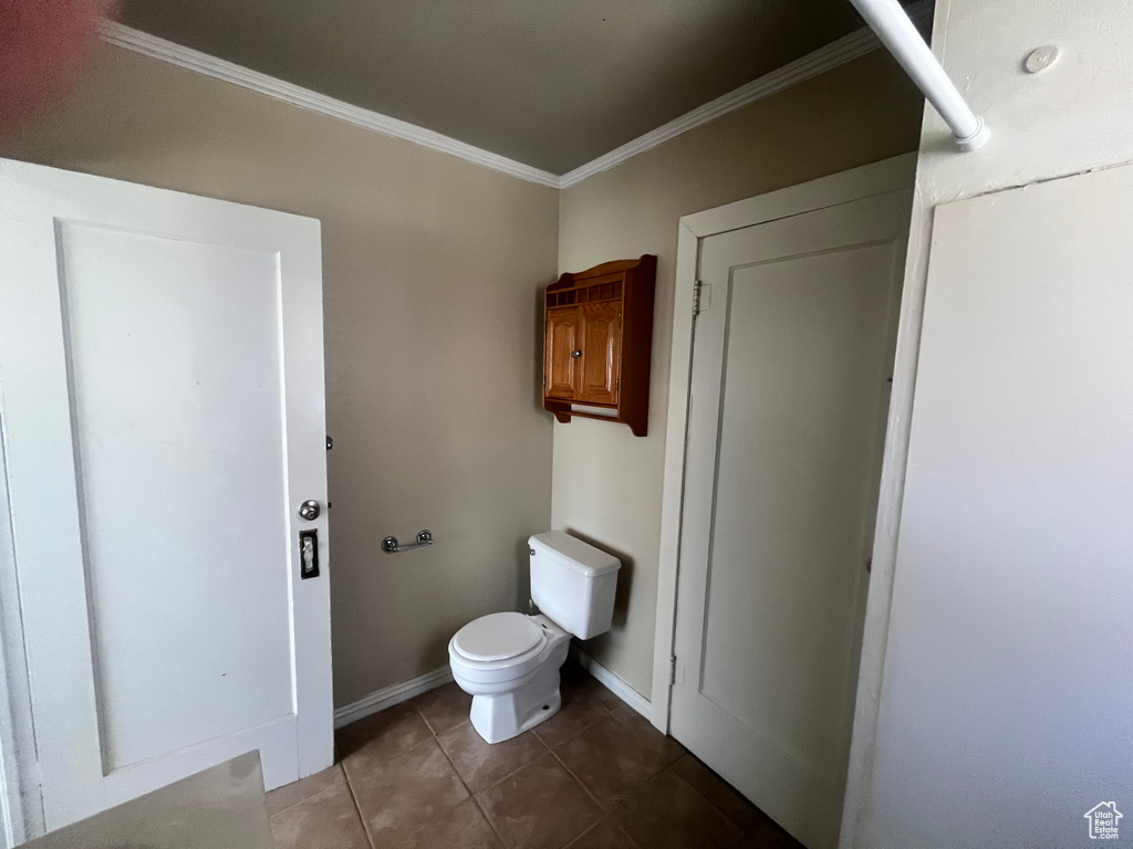 Bathroom with ornamental molding, toilet, and tile flooring