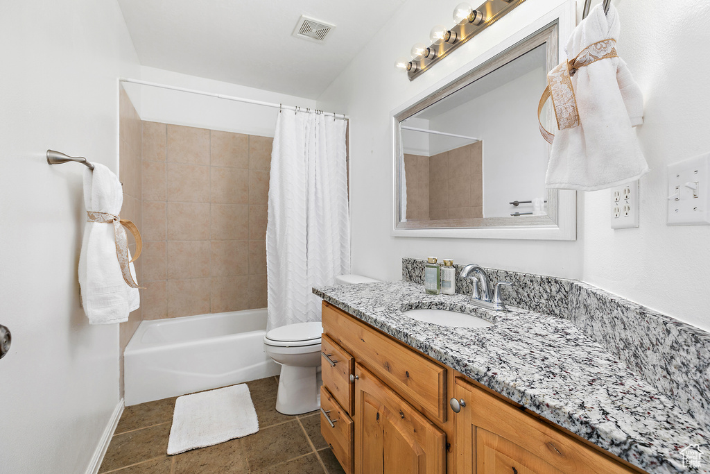 Full bathroom with tile flooring, vanity with extensive cabinet space, toilet, and shower / bath combo with shower curtain