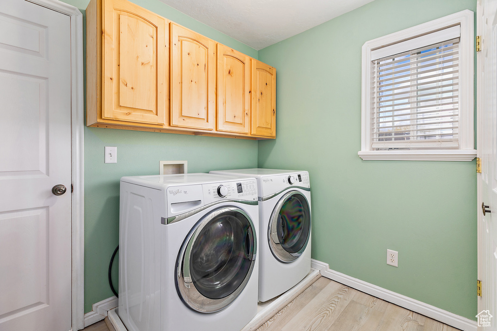 Laundry room featuring cabinets, hookup for a washing machine, light wood-type flooring, and washing machine and clothes dryer