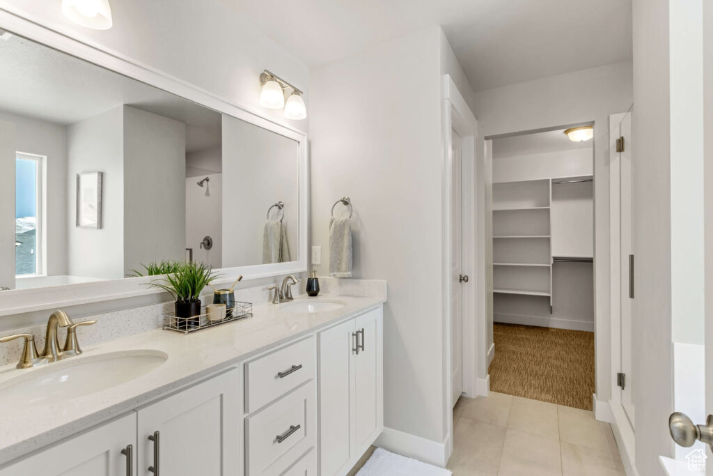 Bathroom with vanity with extensive cabinet space, double sink, and tile floors