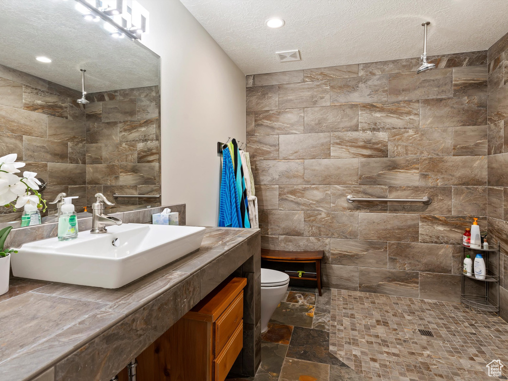 Bathroom with tile walls, oversized vanity, toilet, and tile flooring