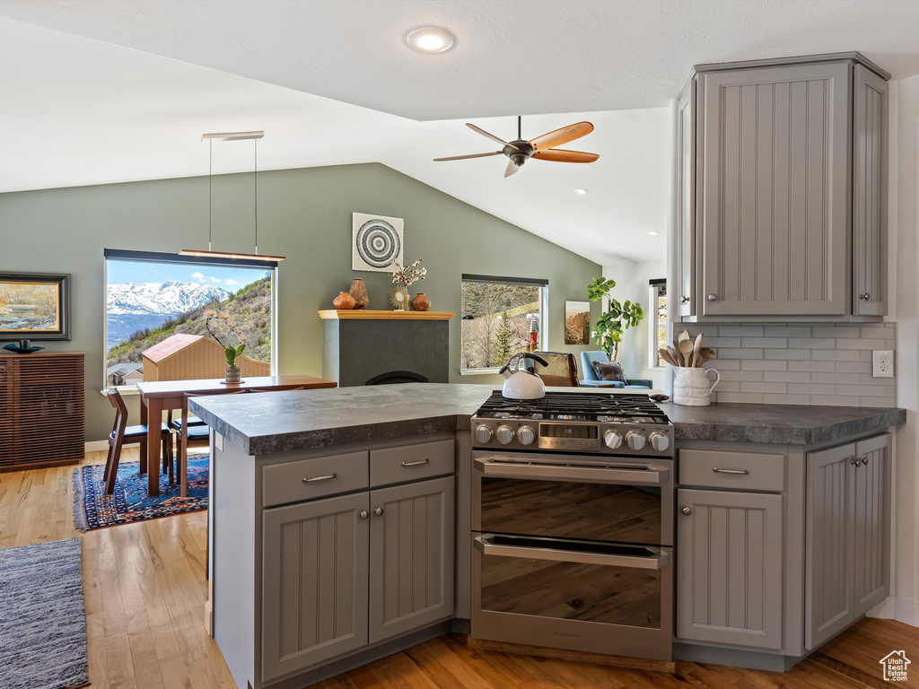 Kitchen featuring gas stove, ceiling fan, light hardwood / wood-style floors, gray cabinetry, and vaulted ceiling