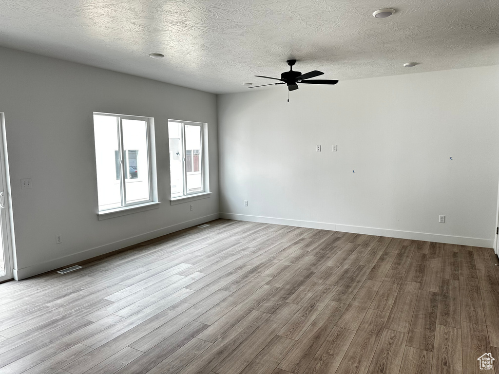 Unfurnished room featuring a textured ceiling, ceiling fan, and light wood-type flooring