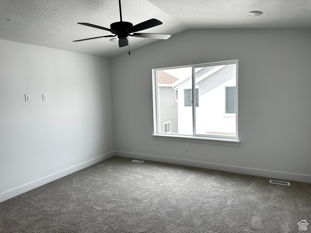 Unfurnished room with a textured ceiling, ceiling fan, carpet floors, and lofted ceiling