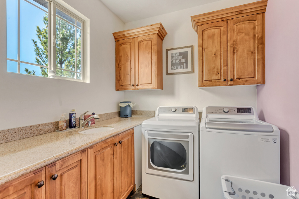 Clothes washing area with sink, cabinets, and washing machine and clothes dryer