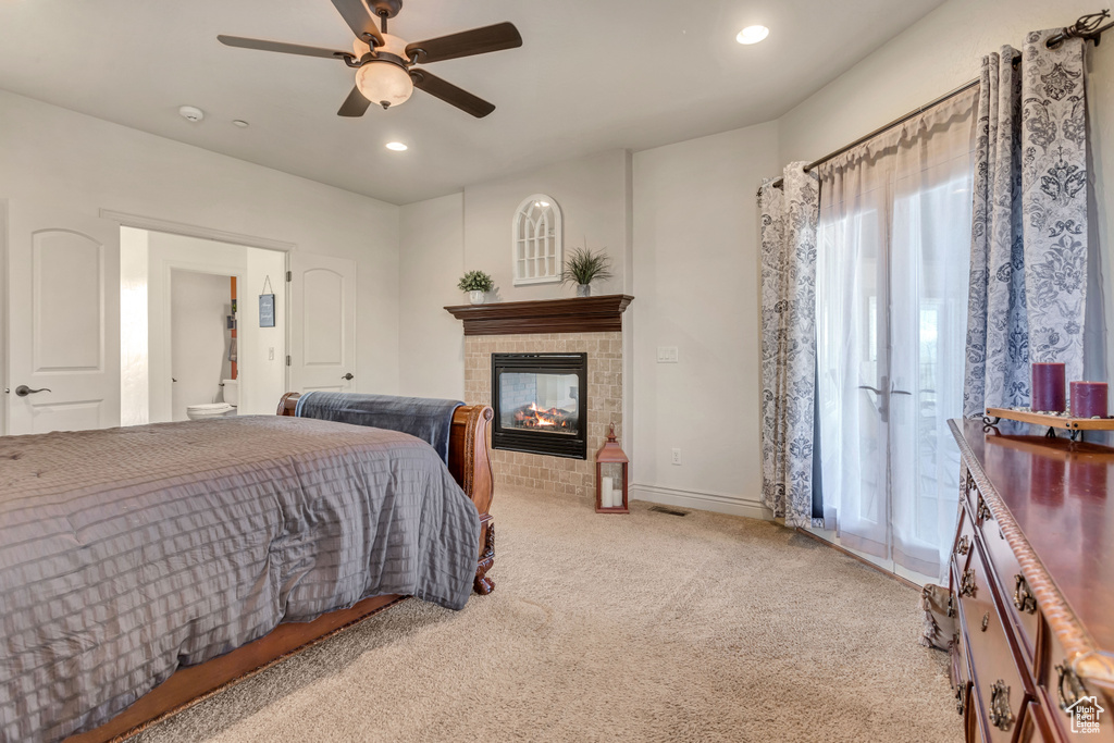 Carpeted bedroom with ceiling fan and a fireplace
