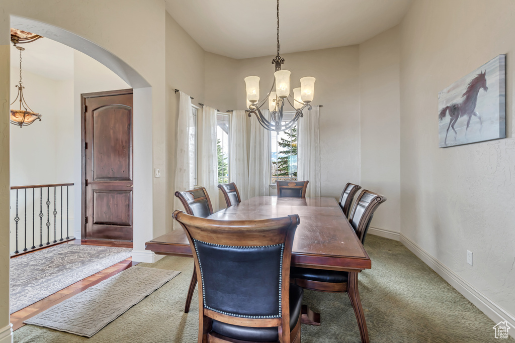 Carpeted dining room with an inviting chandelier