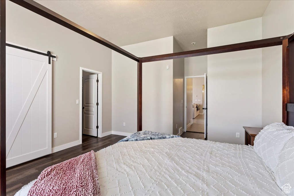 Bedroom with a barn door and dark hardwood / wood-style flooring