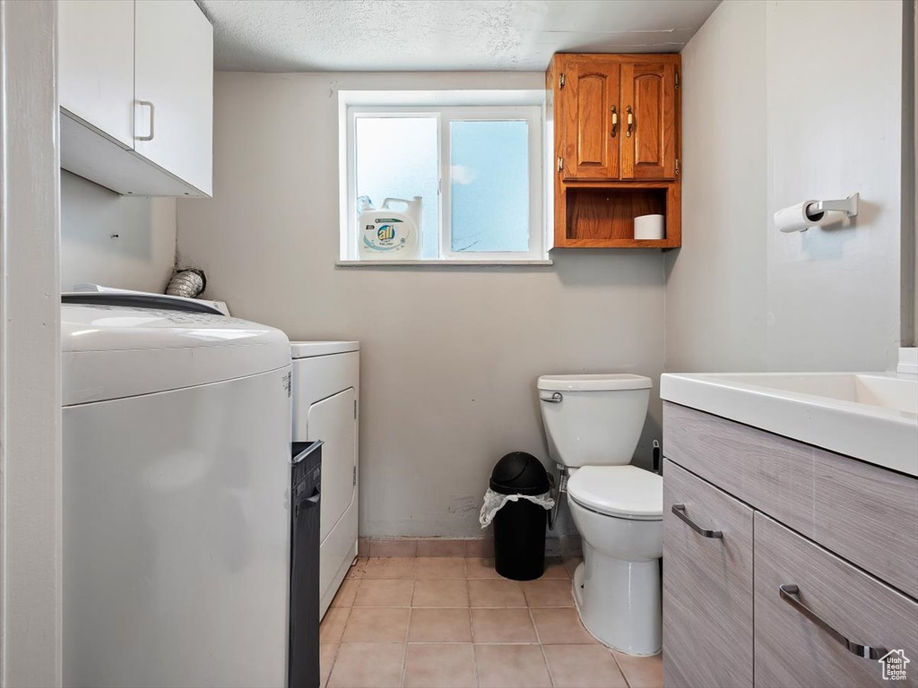 Bathroom featuring tile floors, vanity, toilet, and separate washer and dryer