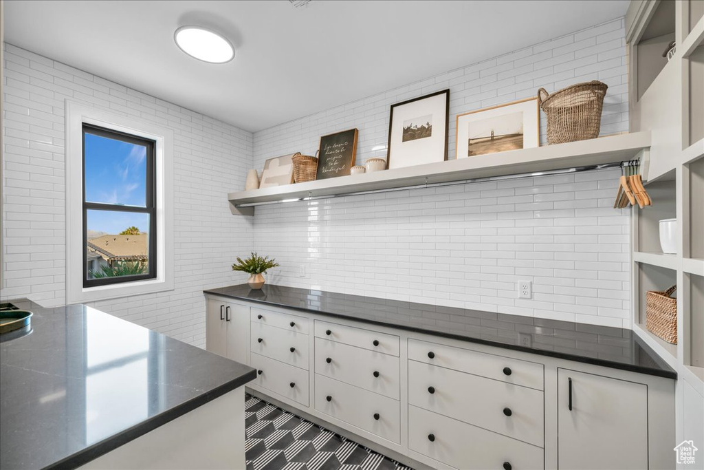 Kitchen featuring white cabinets, backsplash, and tile flooring