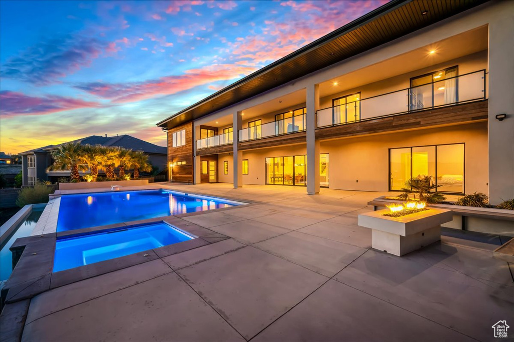 Pool at dusk featuring a patio and an outdoor fire pit