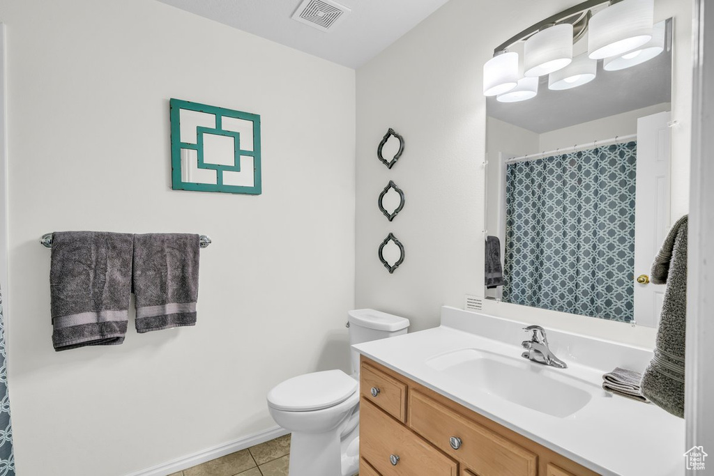 Bathroom with vanity, toilet, a notable chandelier, and tile flooring