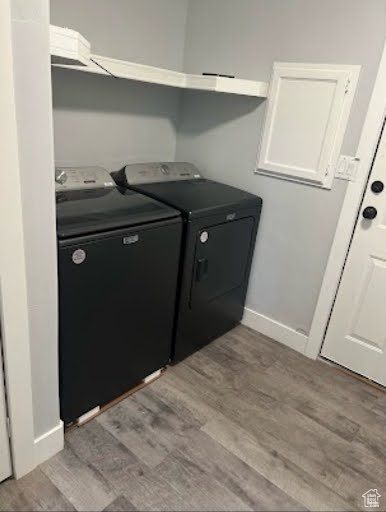 Laundry area with wood-type flooring and washing machine and clothes dryer