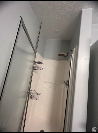 Bathroom featuring walk in shower and a textured ceiling