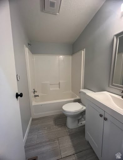Full bathroom with a textured ceiling, large vanity, bathing tub / shower combination, and toilet