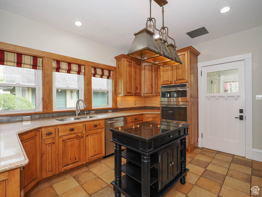 Kitchen featuring sink, light tile floors, stainless steel appliances, and a wealth of natural light