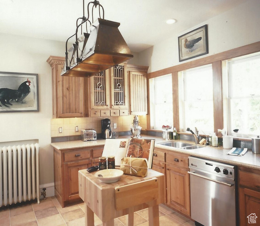 Kitchen featuring radiator heating unit, sink, backsplash, stainless steel dishwasher, and hanging light fixtures