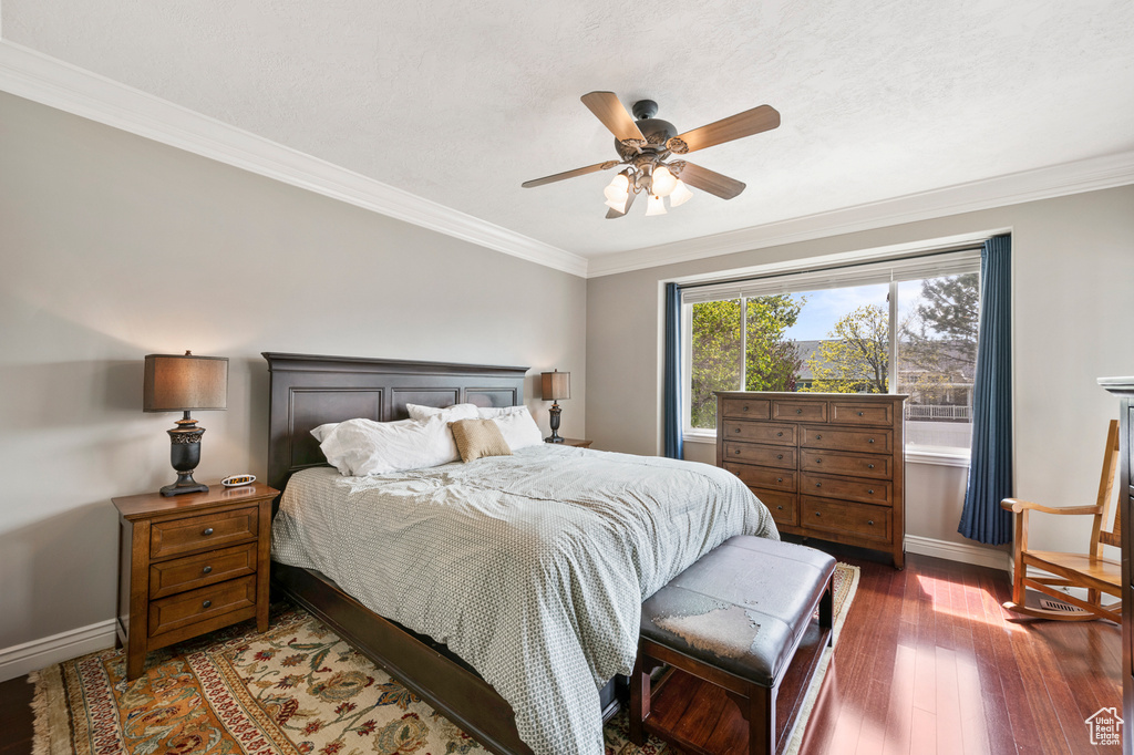 Bedroom with ceiling fan, dark hardwood / wood-style flooring, and ornamental molding